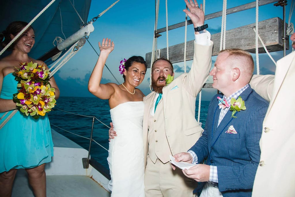 A couple celebrates after getting married on a sailboat. 