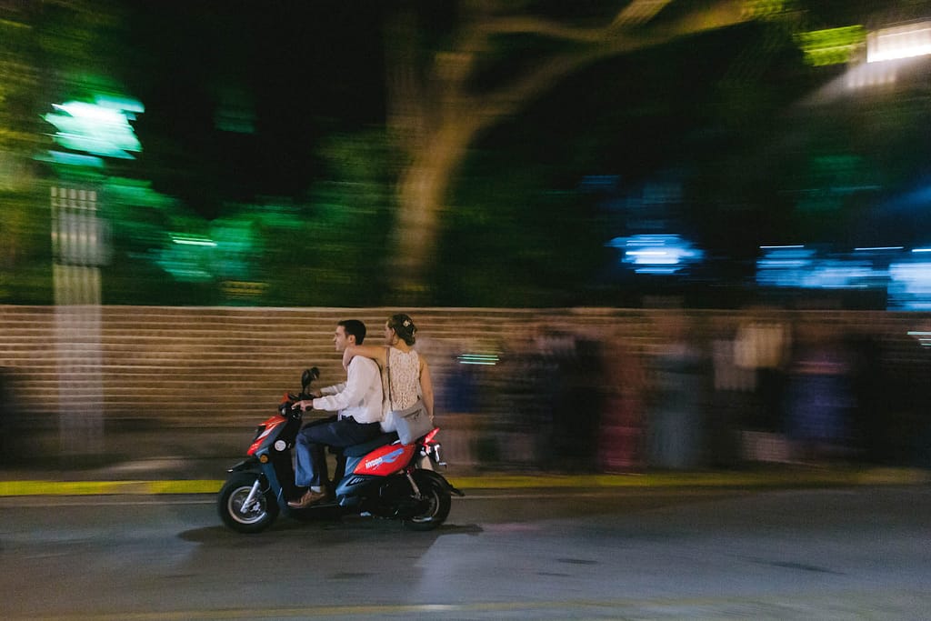 A couple takes a scooter as they leave their wedding reception. 