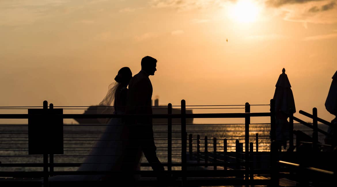 A couple hosting an eco-friendly wedding, strolls at sunset.