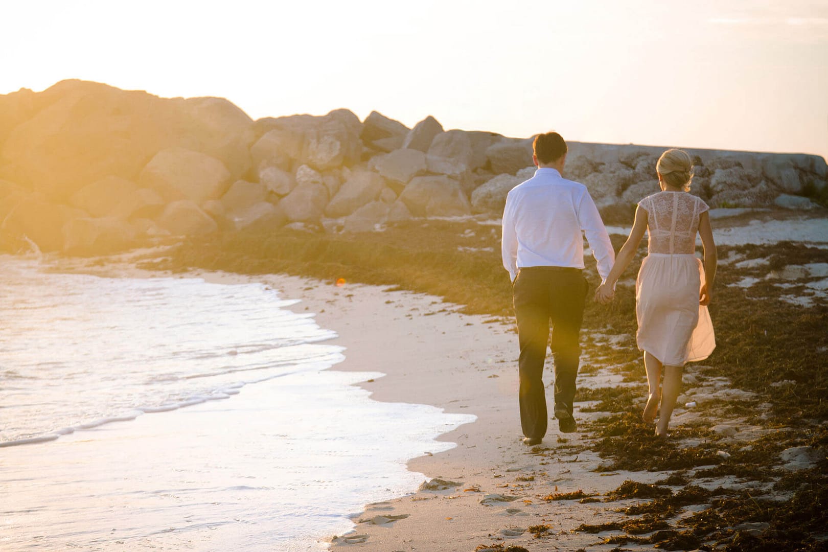 couple who is eloping in key west walks on the beach at sunset.