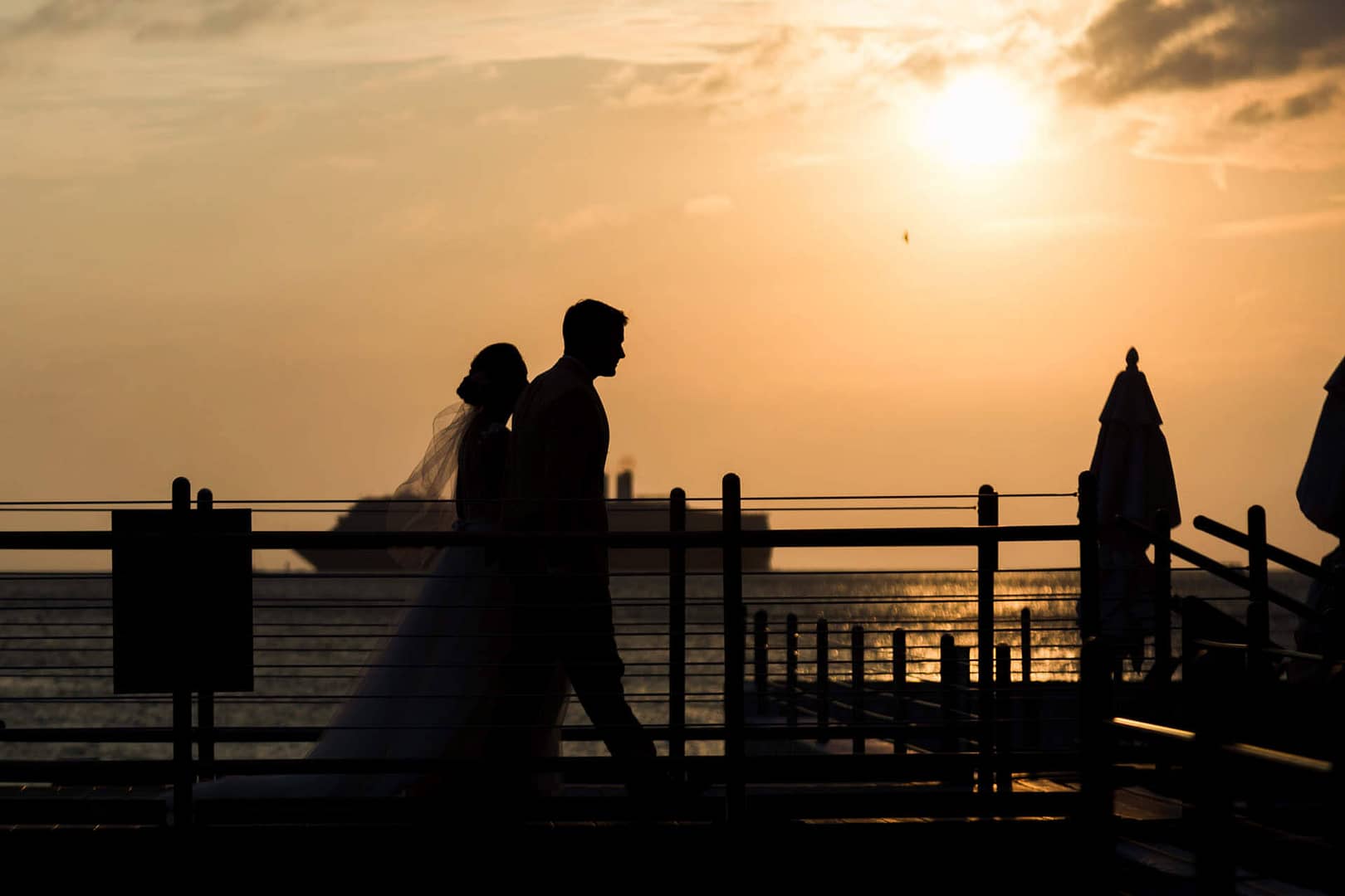 A couple hosting an eco-friendly wedding, strolls at sunset.