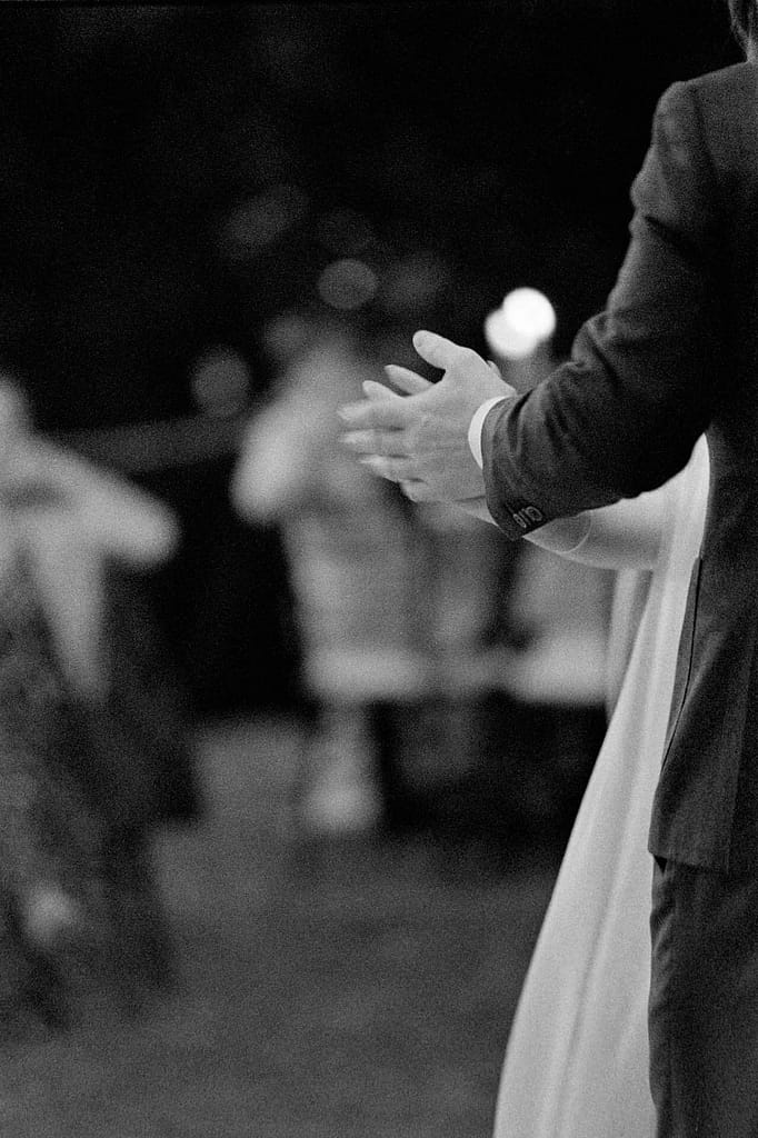 A couple holds hands during their first dance.